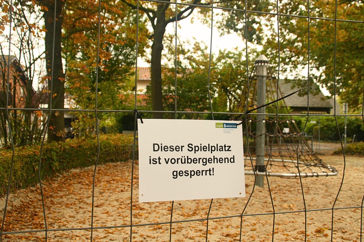 Bauzaun vor einem abgesperrten Spielplatz mit Schild "Dieser Spielplatz ist vorübergehend gesperrt"
