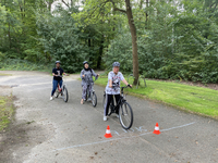 Zwei Mädchen und eine Frau sitzen auf einem Fahrrad in einem Wald oder Park.