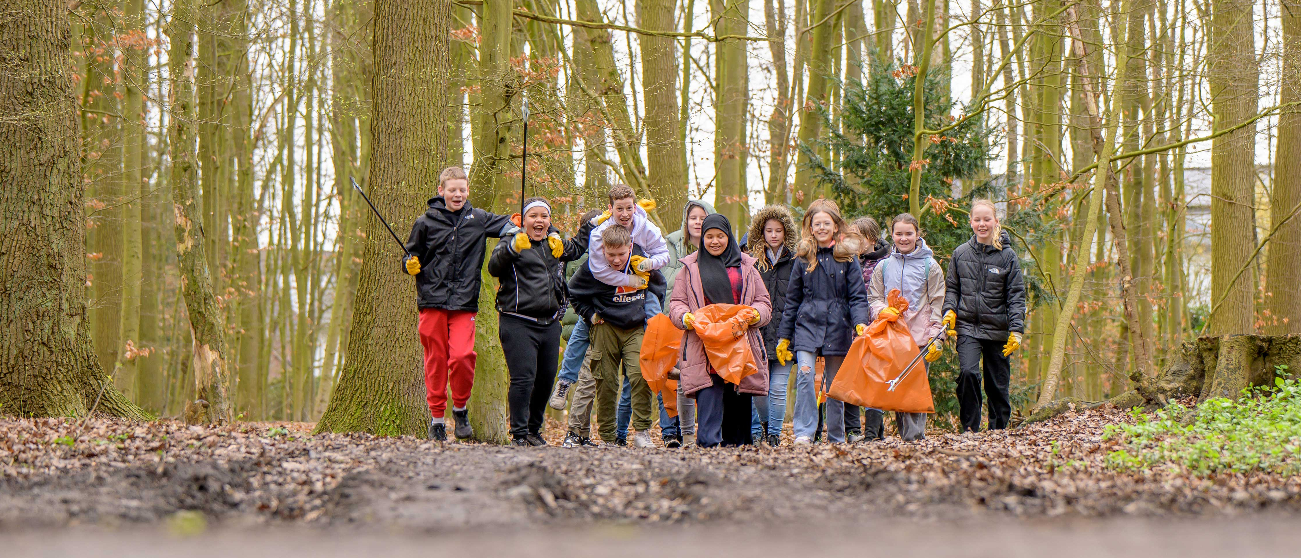 Eine Gruppe Kinder, die an der Aktion Sauberes Münster teilgenommen hat und im Wald Müll sammelt.