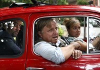 In einem knallrotn Auto sitzen Prof. Karl-Friedrich Boerne (Jan Josef Liefers, li) und Kommissar Frank Thiel (Axel Prahl) und lassen sich von Silke Haller alias 'Alberich' (ChrisTine Urspuch) fahren. Tatort 'Höllenfahrt', Buch Claudia Falk, Regie Tim Trageser, Foto: WDR/Michael Böhme