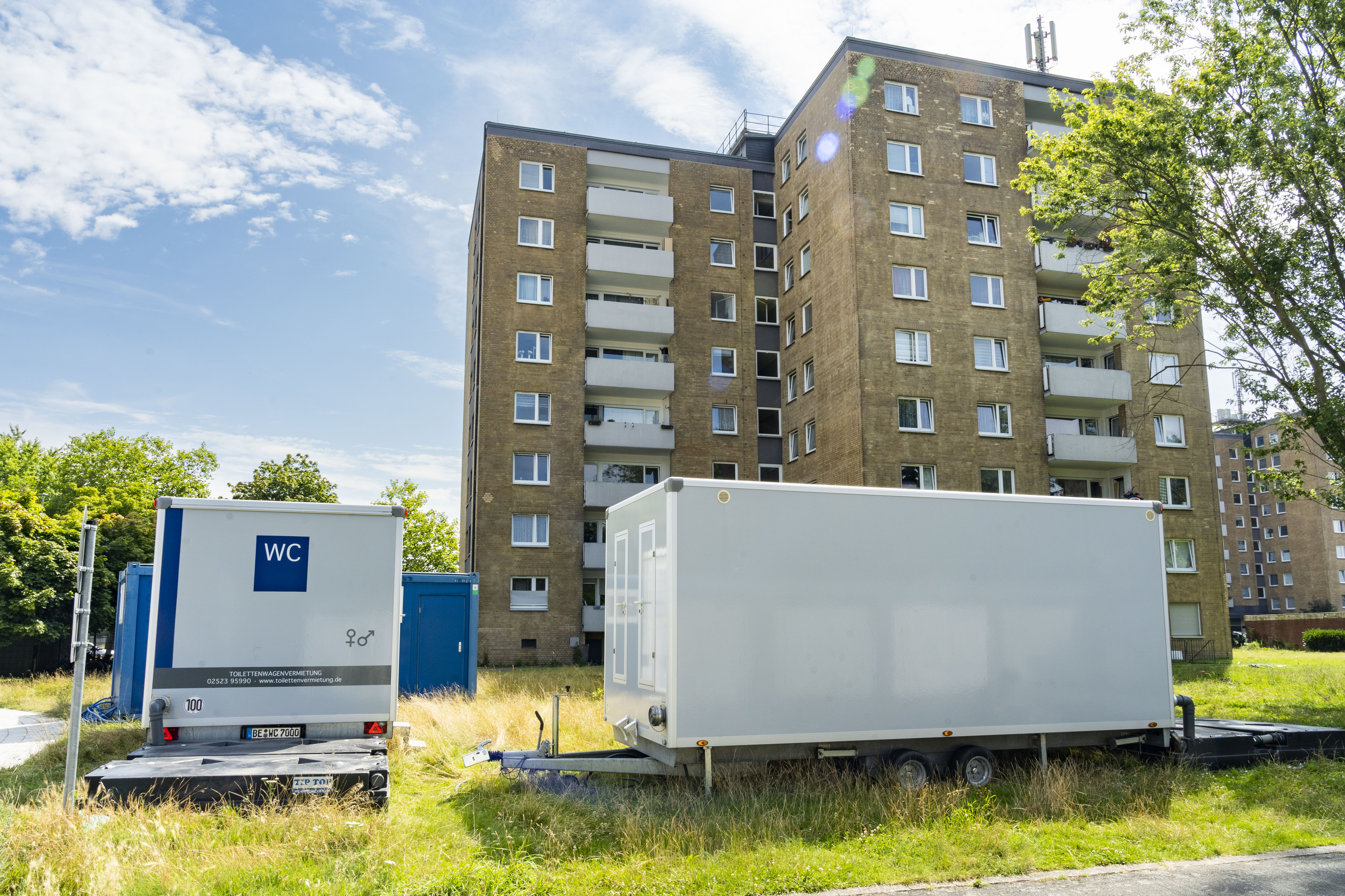 zwei Sanitär- und Duschcontainer vor einem Hochhaus