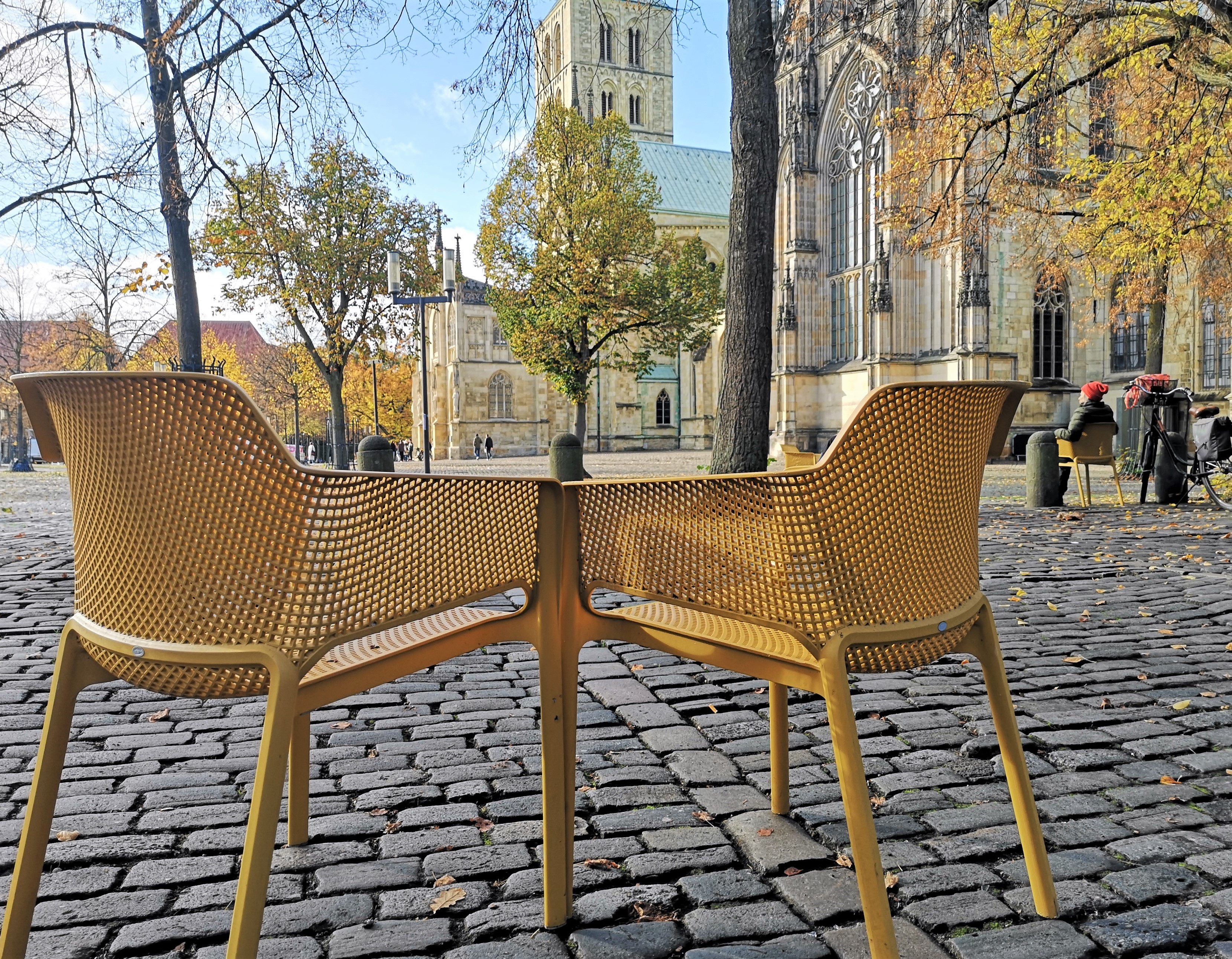 Zwei gelbe Stühle stehen auf einem gepflasterten Platz vor dem Münsteraner Dom
