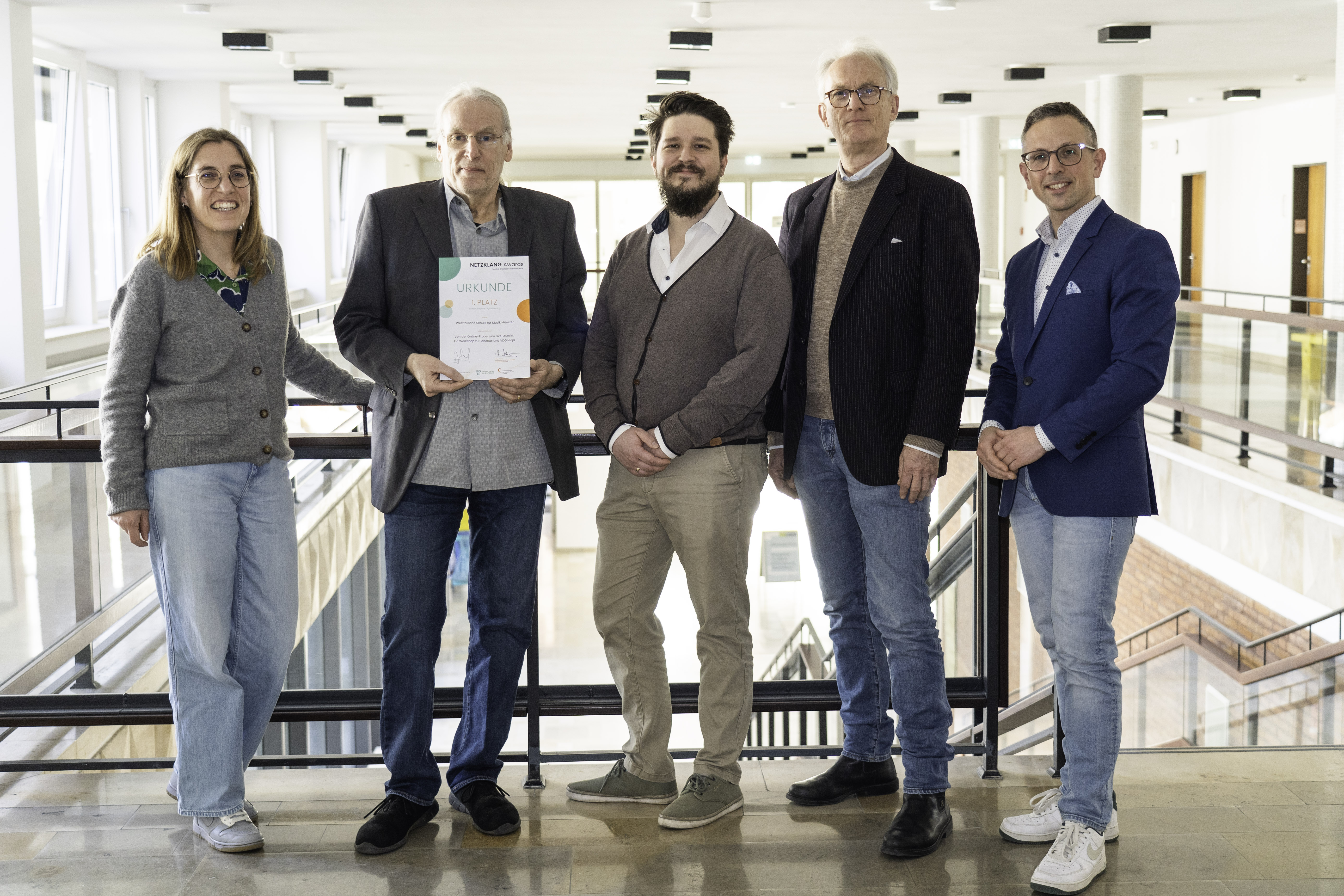 Cornelia Wilkens , Gisbert Keller, Klemens Brüggemann, Lars Motel und Peter Nagy stehen nebeneinander im hellen Treppenhaus des Stadthauses. Gisbert Keller hält die Urkunde mit der Auszeichnung in den Händen.