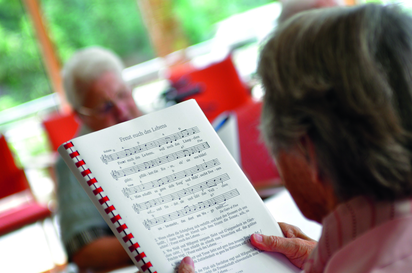 Notenblatt mit singenden Personen im Hintergrund 