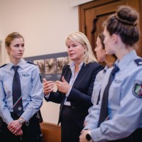 Friederike Zurhausen steht neben zwei Polizistinnen in der Dauerausstellung der Villa ten Hompel