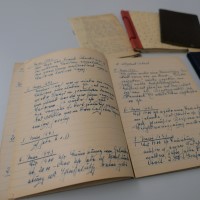 Auf einem Tisch liegt aufgeschlagen ein Tagebuch mit Einträgen aus dem Jahr 1943. Im Hintergrund liegen weitere, schmale Hefte.
