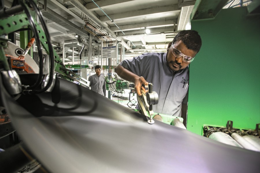 Ein Mitarbeiter arbeitet in einer Industriehalle an einer Dammstoffplatte